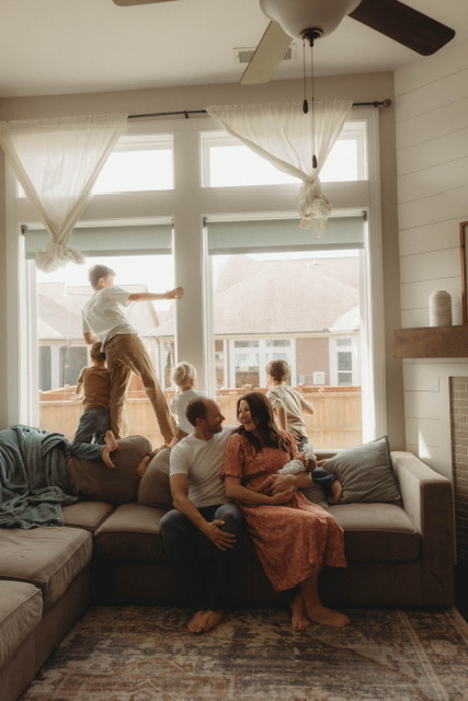 Family of seven relaxing together at home with their newborn baby.